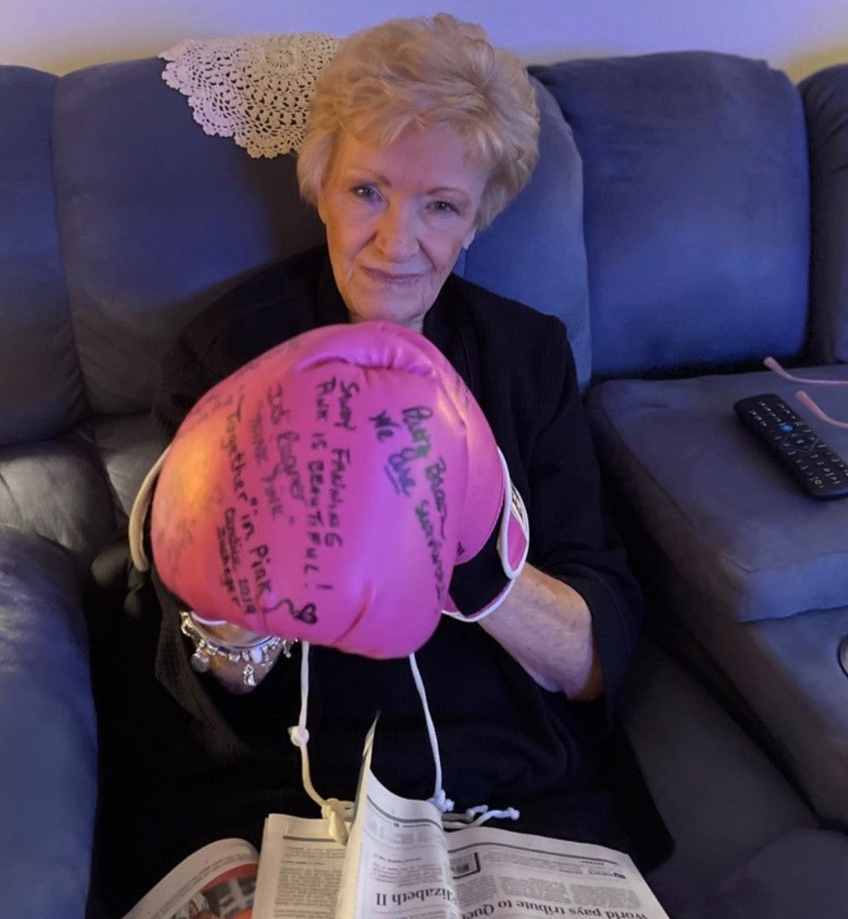 Betty Kabara holding a signed pair of pink boxing gloves.